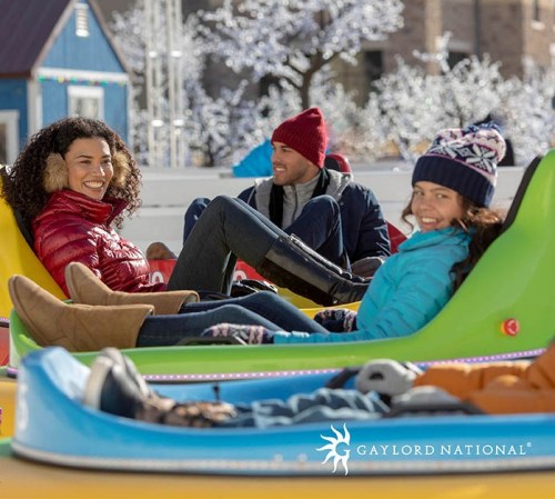 Three friends enjoy a winter day on colorful snow tubes, smiling in a festive outdoor setting.