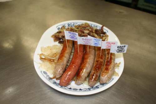 A plate of assorted sausages with labels, served with sautéed onions and sauerkraut.