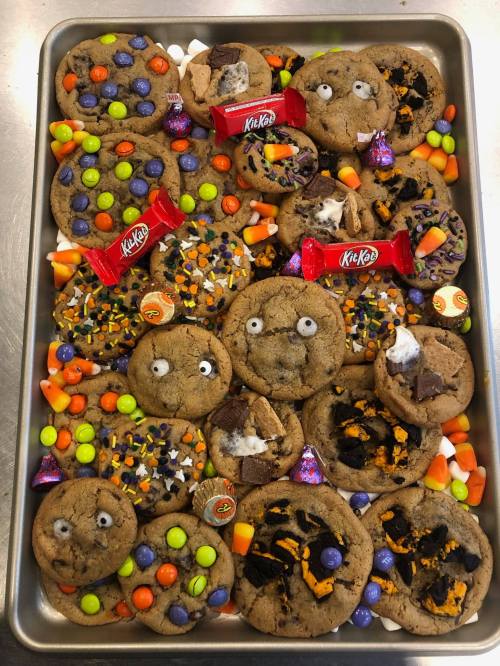 A tray of decorated cookies featuring candy, chocolate, and playful faces, perfect for a festive celebration.