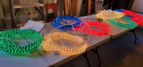 Colorful LED light strips in green, blue, red, and white arranged on a table in a workshop setting.