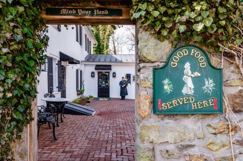 A charming outdoor dining area with a sign reading "Good Food Served Here," framed by ivy-covered stone walls.