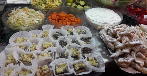 A colorful spread of salads, carrots, and various desserts, including pastries and sweet treats, arranged on platters.