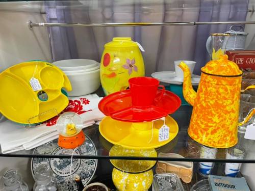 A display of colorful vintage kitchenware, including yellow and red dishes, a teapot, and decorative items.