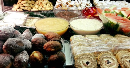 A variety of desserts and fruits displayed, including pastries, cakes, and fresh watermelon slices.