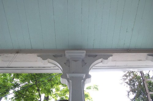 View of a porch ceiling with light blue paint and a decorative white column supporting the structure.