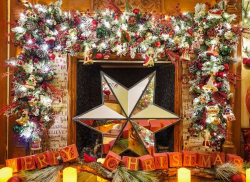 A festive Christmas display featuring a star, garlands, and a "Merry Christmas" sign with candles.