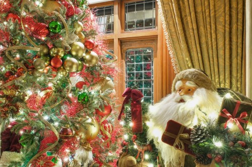 A festive Christmas tree adorned with colorful ornaments and lights, next to a decorative Santa figure.