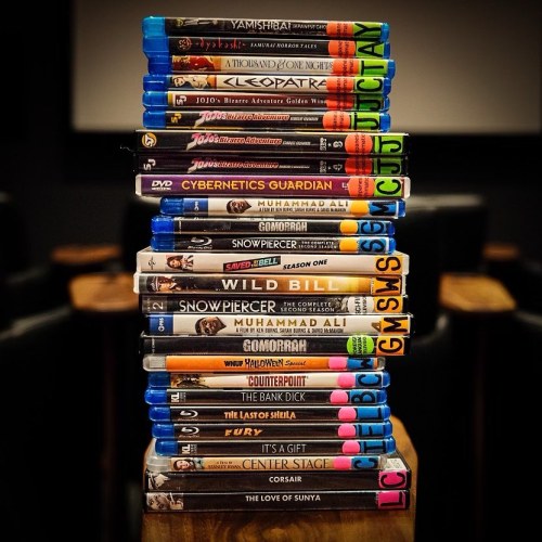 A stack of DVDs and Blu-rays, featuring titles like "Cleopatra," "Snowpiercer," and "Muhammad Ali."