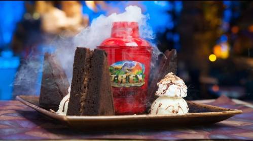 A vibrant dessert featuring a red shaker, chocolate cake pieces, and ice cream, with smoke for a dramatic effect.
