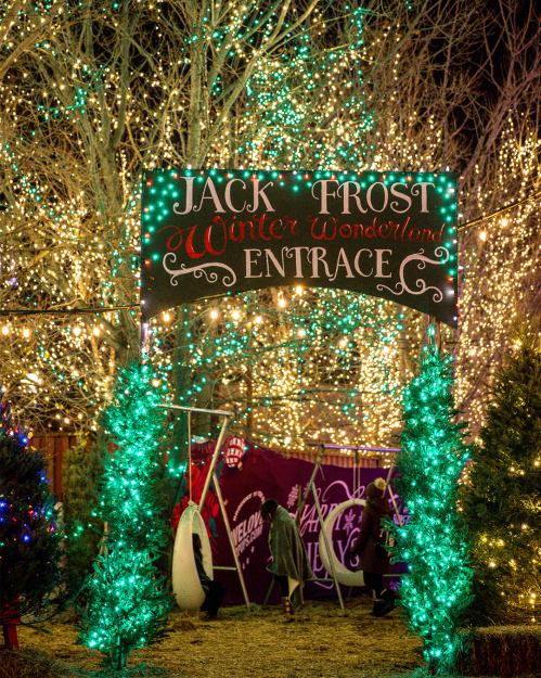A festive entrance sign for "Jack Frost Winter Wonderland" surrounded by colorful lights and decorated trees.