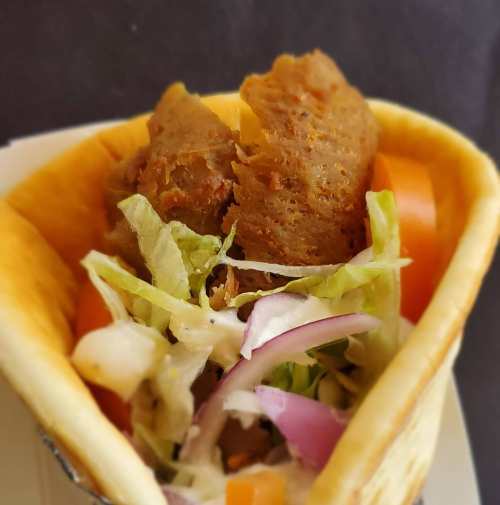 A close-up of a taco filled with lettuce, tomatoes, onions, and a savory meat filling in a soft tortilla.
