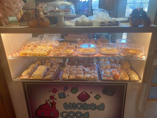 A display case filled with various baked goods, including pastries and pies, under a sign that reads "Wicked Good."