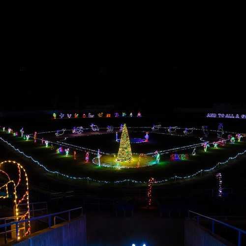 A brightly lit holiday display in a stadium, featuring a central tree and various festive decorations.