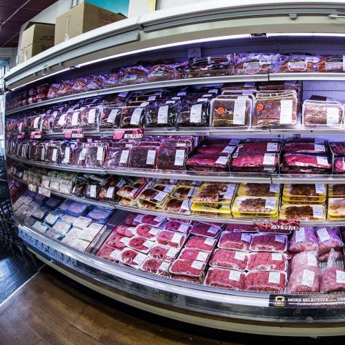 A refrigerated display case filled with various packaged meats and seafood in a grocery store.