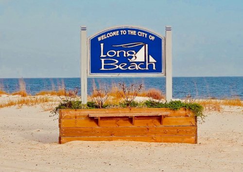 Sign welcoming visitors to Long Beach, with sandy beach and ocean in the background.