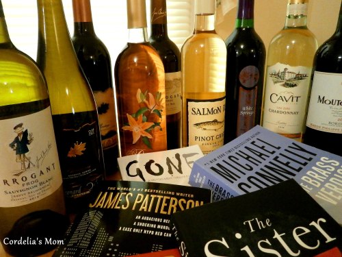 A collection of wine bottles and books arranged on a table, featuring various labels and titles.