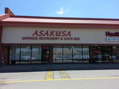 Exterior of Asakusa Japanese Restaurant & Sushi Bar, featuring large windows and a red sign against a blue sky.