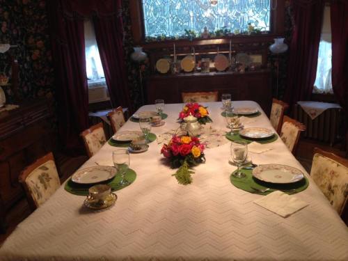 A beautifully set dining table with floral centerpieces, elegant dishware, and green placemats in a cozy room.