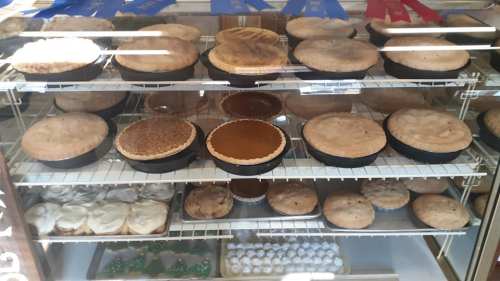 A display case filled with various baked pies and desserts, including round pies and cream-topped treats.