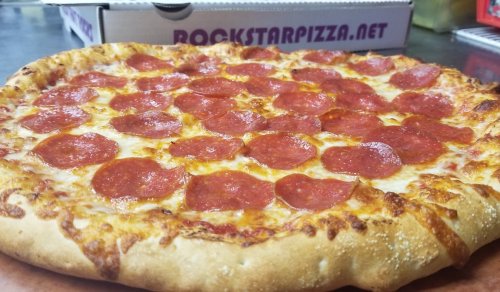 A close-up of a pepperoni pizza with a golden crust and melted cheese, placed on a countertop.
