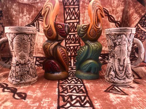 Three decorative mugs with intricate designs, set against a patterned fabric background.