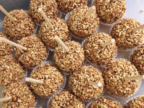 A close-up of round treats coated in chopped nuts, each on a stick and arranged in a neat pattern.