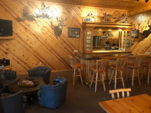 Cozy wooden bar area with mounted deer heads, seating, and a rustic atmosphere.