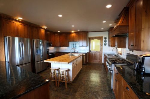 Spacious kitchen with wooden cabinets, stainless steel appliances, a central island, and a door leading outside.