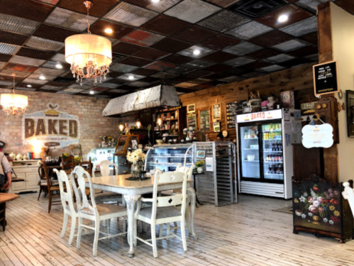 Cozy café interior with rustic decor, a wooden table, vintage furniture, and a display fridge filled with drinks.