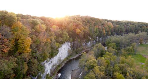 Aerial view of a river winding through a forested landscape with colorful autumn trees and a setting sun.