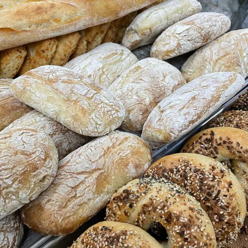 A variety of freshly baked breads, including rolls and bagels, displayed on a tray.