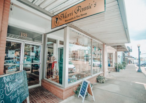 Exterior of Merri Pennie's Tea Room, featuring large windows, a sign, and a chalkboard menu outside.