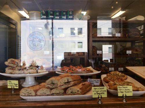 A bakery display featuring various pastries, including sandwiches and baked goods, behind a glass window.