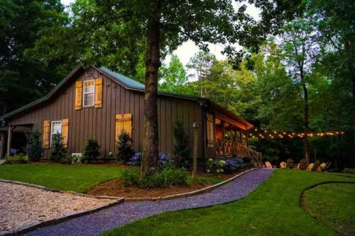 A cozy cabin surrounded by trees, with a pathway leading to a patio adorned with string lights.