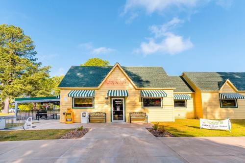 A yellow building with a green roof and striped awnings, featuring benches and a sign for "Stacy's Café."