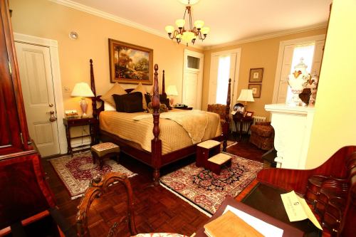 Cozy bedroom with a four-poster bed, warm lighting, and classic decor, featuring rugs and antique furniture.