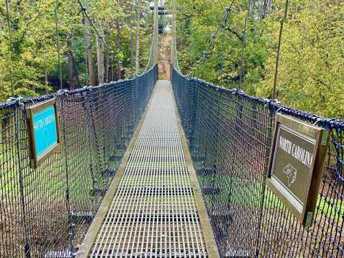 A suspension bridge with signs marking the borders of North Carolina, surrounded by lush greenery.