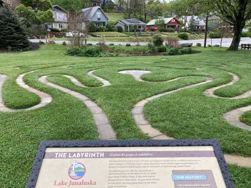 A grassy labyrinth with a sign, surrounded by houses and trees at Lake Junaluska.