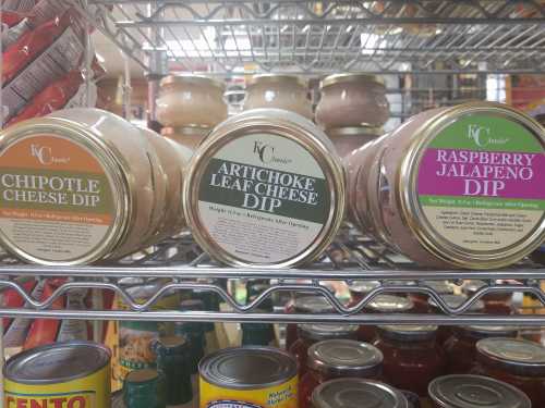 Three jars of dip on a shelf: Chipotle Cheese Dip, Artichoke Leaf Cheese, and Raspberry Jalapeno Dip.