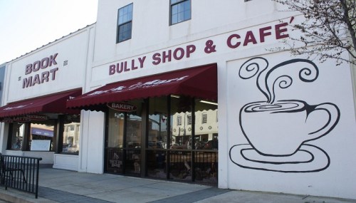 Exterior of a building featuring a bookstore and a café with a coffee cup mural on the wall.