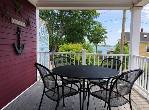 A porch with a round table and chairs, overlooking a scenic view of trees and water in the background.
