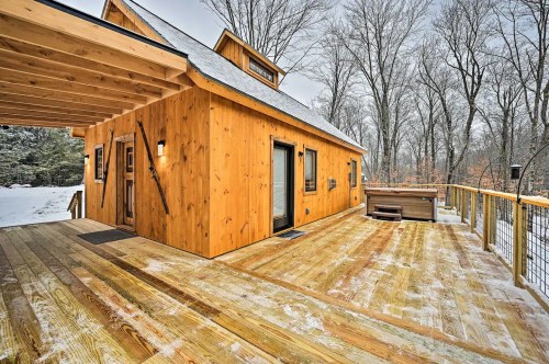 A wooden cabin with a deck, surrounded by snow-covered trees in a winter landscape.