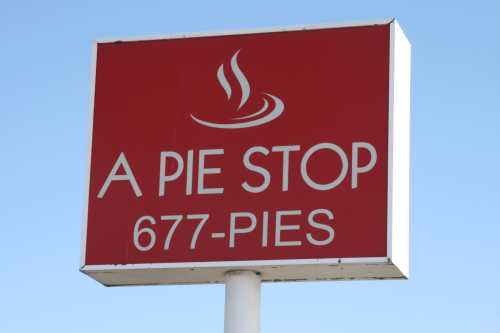 Sign for "A Pie Stop" with the phone number 677-PIES against a clear blue sky.