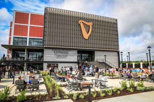 Exterior of the Guinness Open Gate Brewery with people enjoying the outdoor seating area on a sunny day.