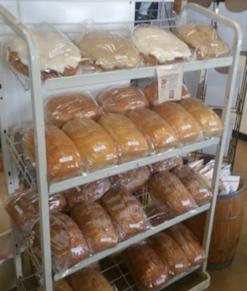 A display rack with several loaves of bread, some with icing, neatly packaged and arranged in rows.