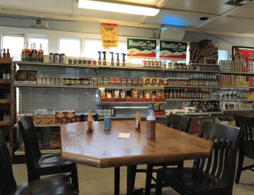 A cozy dining area with a wooden table and chairs, surrounded by shelves of canned goods and condiments.
