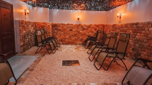 A cozy relaxation room with reclining chairs, stone walls, and soft lighting, creating a tranquil atmosphere.