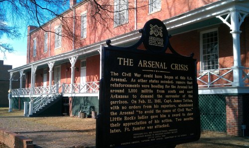 Historic building with a sign about the Arsenal Crisis during the Civil War, surrounded by trees and grass.