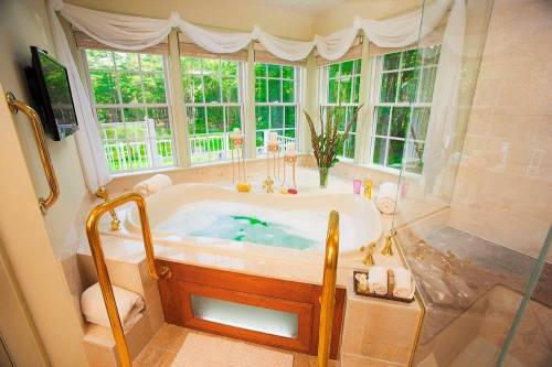 A luxurious bathroom featuring a large whirlpool tub, elegant decor, and large windows with a view of greenery outside.