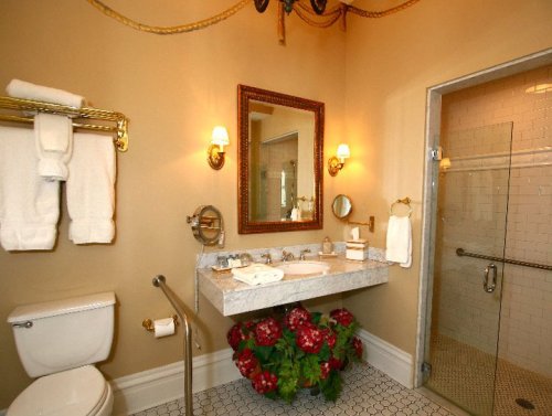 Elegant bathroom featuring a marble sink, gold fixtures, a shower, and decorative plants. Soft lighting enhances the ambiance.